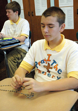 Holy Name School eighth-grade students Ben Coons, right, and Jake Farnworth, left, of Beech Grove pray a decade of the rosary on Jan. 13 during religion class. Ben, Jake and other classmates recently decorated T-shirts with the message &ldquo;I pray the rosary&rdquo; to promote their Catholic faith as well as their devotion to Jesus and Mary. (Photo by Mary Ann Wyand)