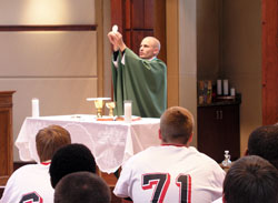 Father John Hollowell celebrates Mass on Sept. 25, 2009, for members of the varsity football team of Cardinal Ritter Jr./Sr. High School in Indianapolis. As a chaplain, teacher and assistant football coach at Cardinal Ritter, Father Hollowell celebrates Mass on the Friday afternoon before every football game&mdash;continuing the emphasis that head coach Ty Hunt has of making faith a crucial part of the teenagers&rsquo; football experience. (Photo by John Shaughnessy)