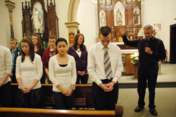 Father John Meyer, right, the pastor of Prince of Peace Parish in Madison, blesses teenagers who were preparing to participate in the 37th annual March&nbsp;for Life in Washington during a Jan. 17 prayer service at St. Patrick Chapel in Madison. Youth ministry coordinator Joe Stilwell, second from right, also teaches religion classes at Shawe Memorial Jr./Sr. High School in Madison. (Photo by Mary Ann Wyand)