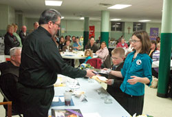 Father Christopher Craig, pastor of St. Joseph Parish in Shelbyville, receives gifts from first-grader Dakota Sosbe, left, and sixth-grader Makayla&nbsp;Schacht, both participants in St. Joseph&rsquo;s religious education program, during a Year&nbsp;for Priests event on March 6 at the Batesville Deanery parish. (Photo by Sean Gallagher)