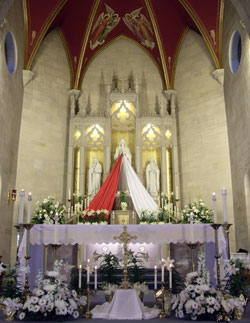 Red and white banners flow down from a statue of Jesus to make it appear like the image of Divine Mercy in 2008 in the sanctuary of St.&nbsp;Vincent de Paul Church in Bedford. Parishes across the archdiocese will hold Divine Mercy services on April 11, which is Divine Mercy Sunday. (Submitted photo)
