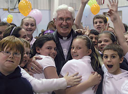Students at St. Roch School in Indianapolis rejoice with Father James Wilmoth following a school-wide tribute on April 8 that celebrated their pastor.&nbsp;The school celebration recognized Father Wilmoth&rsquo;s selection as one of the 10 priests from across the United States who recently received the Distinguished Pastor Award from the National Catholic Educational Association. (Photo by John Shaughnessy)