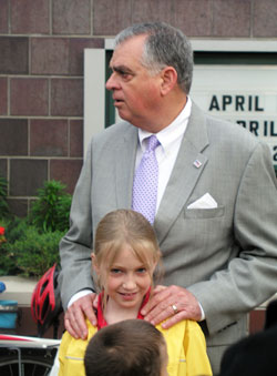 U.S. Transportation Secretary Ray LaHood rests his hands on the shoulders of his granddaughter, Ella Gebke, on April&nbsp;23, a day that marked the observance of two special events at St. Thomas Aquinas School in Indianapolis&mdash;Grandparents&rsquo; Day and the celebration of the &ldquo;Safe Routes to School&rdquo; program. LaHood is the grandfather of Ella, a second-grade student at St. Thomas, and Henry, a kindergarten student. (Photo by John Shaughnessy)