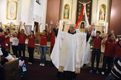 Franciscan Father Arturo Ocampo, pastor of St. Patrick Parish in Indianapolis, sings with youths and young adults involved in Las Jornadas, a Hispanic lay movement in the Church, at the start of an April 18 Mass at his parish&rsquo;s church. (Photo by Sean Gallagher)