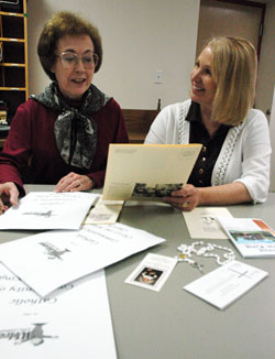 Christ the King Parish staff members Rose Sterger, left, and Melissa&nbsp;Buechler of Indianapolis prepare new member welcome packets that include a rosary, holy card of St. Theodora Gu&eacute;rin, Mass schedule and other parish information to help newcomers connect to the faith community. (Photo by Mary Ann Wyand)
