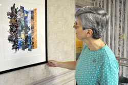 Benedictine Sister Carol Falkner, administrator of the Benedict Inn Retreat and Conference Center in Beech Grove, looks at a print of an illustration for the Book of Genesis from The Saint John&rsquo;s Bible exhibit on Aug. 2. The exhibit features artwork and calligraphy by Welsh artist Donald Jackson as well as an exhibit of historic religious manuscripts on loan from John Lawrence of Evansville, Ind., who is an art conservator and consultant on Medieval and Renaissance artifacts. The Bible exhibit is free and on display from Aug. 6-29. (Photo by Mary Ann Wyand)