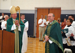 Archbishop Daniel M. Buechlein leads members of SS. Francis and Clare of Assisi Parish in Greenwood in applauding the parish&rsquo;s pastor, Father Vincent Lampert, on Aug. 8 for his hard work and ministry in leading the faith community during its rapid expansion over the past four&nbsp;years. Standing behind Archbishop Buechlein, from left, deacons Stephen Hodges and Ronald Reimer join in the applause. (Photo by Sean Gallagher)