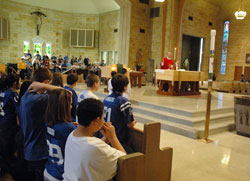 Students at Little Flower School in Indianapolis kneel in prayer during a Feb. 5, 2010, Mass at St. Therese of the Infant Jesus (Little Flower) Church while&nbsp;Father Robert Gilday, pastor of the parish, prays the eucharistic prayer. During the Mass, students gave cards of appreciation to Father&nbsp;Gilday. Making the cards was part of a parish-wide program to help all parishioners learn about the sacraments. (File photo by Sean Gallagher)