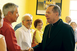 Archbishop Daniel M. Buechlein, right, shakes hands with Brett Sciarra, left, a member of St. Ambrose Parish in Seymour, on June 27 at the parish. Fred Sciarra, second from left, his father, and Arlene&nbsp;Calmer look on. (Photo by Jamie Marshall/Marshall Memories)