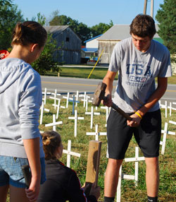 St. Joseph parishioner Brian Weigel of St. Leon pounds a cross into the ground with the help of&nbsp;another youth in the parish on Sept. 18 along Route 1 just south of Interstate 74 in Dearborn&nbsp;County. The &ldquo;Cemetery of the Innocents&rdquo; display of 4,000 crosses represents the number&nbsp;of babies&nbsp;that die in legalized abortion each day in the United States. The traveling pro-life exhibit will&nbsp;be on display in St.&nbsp;Leon through Oct. 2. (Submitted photo)