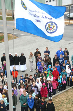 Students of Our Lady of the Greenwood&nbsp;School raise a special flag&nbsp;proclaiming it a Blue Ribbon School of Excellence during a Nov.&nbsp;19 ceremony with staff members. (Photos by Tony Cooper)