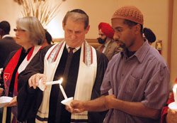 Giora Sharon, center, the cantor and choir director for the Congregation Beth-El Zedeck synagogue in Indianapolis, lights a candle from the candle of Shakoor Siddeeq, the treasurer of the Nur Allah Islamic Center in Indianapolis, during the 11th&nbsp;annual Interfaith Thanksgiving Service on Nov. 23 at SS. Peter and Paul Cathedral in Indianapolis. (Photo by Sean Gallagher)