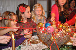 Anna Johnson, from left, Caroline&nbsp;Burns, Mary Monesmith and Kate&nbsp;Johnson of Indianapolis pull ribbons tied to Christmas ornaments from a crystal punch bowl to see if they will be crowned the &ldquo;queen&rdquo; of the tea party hosted by Leigh&nbsp;Dunnington-Jones to celebrate the feast of the Epiphany of the Lord on Jan. 6. (Photo by Mary Ann Wyand)