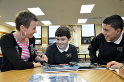 St. Philip Neri School teacher Tara DeRossett of Indianapolis helps sixth-grader Kevin Chaparro, center, and seventh-grader Sergio&nbsp;Sevilla read a book on Jan. 19 at the Indianapolis East Deanery grade school. The boys are from Mexico, and began classes at St. Philip Neri School in November. (Photo by Mary Ann Wyand)