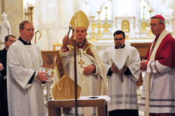 Archbishop Daniel M. Buechlein blesses the episcopal ring, miter and crosier on Feb. 28 that Bishop-designate Christopher J. Coyne, right, would ritually receive during his March 2 ordination at St. John the Evangelist Church in Indianapolis. Assisting the archbishop are Father Patrick Beidelman, left, the archdiocesan director of liturgy, and Ford Cox, second from right, the executive&nbsp;assistant to the archbishop and liaison for episcopal affairs. (Photo by Mary Ann Wyand)