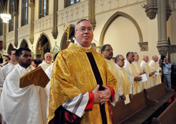 Bishop-designate Christopher J. Coyne smiles at family members and friends from the Archdiocese of Boston as he processes up the aisle on March 2 at St. John the Evangelist Church in Indianapolis for his episcopal ordination Mass. Walking behind Bishop Coyne is Cyrus Sethna of St. Margaret Mary Parish in Westwood, Mass., who&mdash;along with his twin brother, Reggie&mdash;assisted as an altar server during the liturgy. (Photo by Mary Ann Wyand)
