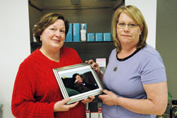 Teresa Bryan, left, and Carolyn Smith hold a photo of their sister, Ruth Anne Arajuo, who died of cancer in 2005. Arajuo is the inspiration for Smith&rsquo;s decision to provide free weekly services to cancer patients at her Indianapolis salon that offers pedicures, manicures, facials and massages. (Photo by John Shaughnessy)