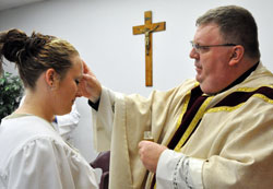 Heather, who is incarcerated at the Indiana Women&rsquo;s Prison in Indianapolis, receives the sacrament of confirmation from Father Robert Robeson on Easter in a chapel at the state correctional facility. Two women were baptized and five women received the sacraments of confirmation and the Eucharist during the April 24 liturgy. (Photo by Mary Ann Wyand)