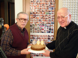 Standing in the studio of WHOJ 93.1 FM on March 12, Ron Eldred, left, and Msgr. Lawrence Moran hold a cake honoring Msgr.&nbsp;Moran&rsquo;s 600th show broadcast on the Terre Haute-based Catholic&nbsp;radio station. Its studio is in the rectory of St. Patrick Parish in Terre Haute. Eldred, who teaches religion and history at John Paul II High School in Terre Haute, has helped produce hundreds of Msgr. Moran&rsquo;s shows. (Submitted photo)