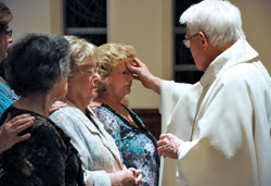 Msgr. John Duncan, chaplain at the St. Augustine Home for the Aged in Indianapolis, places chrism oil on resident Jackie Cooper&rsquo;s forehead as part of the sacrament of confirmation during the Easter Vigil on April 23 at the chapel in the home operated by the Little Sisters of the Poor. St. Augustine Home residents Rita Flowers, left, and Helen Marsh were also confirmed and received first holy Communion. (Photo by Mary Ann Wyand)