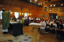 Father Thomas Kovatch, pastor of St. Teresa Benedicta of the Cross Parish in Bright, elevates the Body and Blood of Christ during a June 15 Mass as part of Bishop Brut&eacute; Days, an annual vocations retreat and camping experience for junior high and high school-aged youths sponsored by Bishop Simon Brut&eacute; College Seminary in Indianapolis. It was held from June 14-17 at the Indiana Future Farmers of America Leadership Center in southern Johnson County, and attracted more than 40 participants from across the archdiocese and beyond. (Photo by Sean Gallagher)