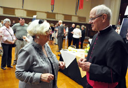 Msgr. Paul Richart, right, pastor of St. Paul Parish in Sellersburg, greets Joyce Gambrall, a member of the New Albany Deanery faith community, during an Aug. 14 reception at the Archbishop O&rsquo;Meara Catholic Center Assembly Hall in Indianapolis after he was honored as a monsignor by Bishop Christopher J. Coyne, auxiliary bishop and vicar general, during an Evening Prayer liturgy at SS. Peter and Paul Cathedral. Msgr. Richart served as an Air Force chaplain for 29 years and achieved the rank of colonel. (Photo by Sean Gallagher)
