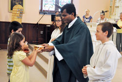 Father Sengole Thomas Gnagnaraj receives offertory gifts from Luke and Elizabeth Geraci during a Sept. 4 Mass at St. John the Baptist Church in Dover. He is assisted by altar servers Olivia and Glenn Geraci, who are Luke and Elizabeth&rsquo;s siblings. Father is associate pastor of the parishes of St. John the Baptist in Dover, St. Joseph in St. Leon, St. Martin in Yorkville and St. Paul in New Alsace. (Photo by Sean Gallagher)