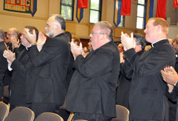 Fathers Peter Marshall, from left, James Farrell, Robert&nbsp;Robeson and Patrick Beidelman stand and applaud Archbishop Emeritus Daniel M. Buechlein after he announced his early retirement for health reasons during the Sept. 21 press conference at the Archbishop O&rsquo;Meara Catholic Center in Indianapolis. (Photo by Sean Gallagher)