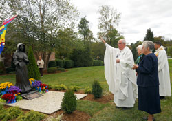 Msgr. Joseph Schaedel, pastor of St. Luke the Evangelist Parish in Indianapolis, blesses a six-foot bronze statue of St. Theodora Gu&eacute;rin at the conclusion of a Mass on the campus of Providence Self Sufficiency Ministries (PSSM) in Georgetown. The Mass was celebrated as part of the dedication of the campus. Assisting Msgr. Schaedel are, from left, Providence Sisters Maria Smith and Barbara Ann Zeller, president and CEO of PSSM, and Father Juan Valdes, administrator of St. Mary Parish in Lanesville. (Photo by Patricia Cornwell)