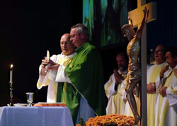 Bishop Christopher J. Coyne, apostolic administrator, center, and Deacon Lawrence French, left, elevate the Eucharist at the conclusion of the eucharistic prayer during a Mass celebrated on Oct. 29 at the Indiana Convention Center in Indianapolis. The Mass was part of the Indiana Catholic Men&rsquo;s Conference that drew more than 800 men and young men from across the state. (Photo by Bryce Bennett)