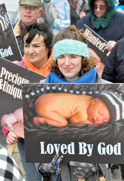 Elizabeth Jamison, center, associate director of vocations for the archdiocese, and more than 400 other pro-life supporters from parishes in central and southern Indiana brave the cold during the archdiocese&rsquo;s second annual Local Solemn Observance and Respect Life March on Jan. 23 in Indianapolis to peacefully protest the 39th anniversary of Roe v. Wade, the tragic Supreme Court decision that legalized abortion in the United States during all nine months of pregnancy. (Photo by Mary Ann Garber)