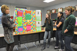 Jill Mires, left, principal of Pope John XXIII School in Madison, speaks with sixth-grade students Summer Martin, Leigh Ann Gaminde and Erin Cooper on Jan. 11 about a presentation board created for the CLASS (&ldquo;Connecting Learning Assures Successful Students&rdquo;) program. (Photo by Sean Gallagher)