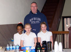Bishop Christopher J. Coyne proudly wears his New England Patriots hoodie as he poses with St. Lawrence School students Morgen Harris, left, Ashleigh Wade and Ema O’Hara on Jan. 30. The students were serving coffee and donuts to staff at the Archbishop Edward T. O’Meara Catholic Center in Indianapolis during Catholic Schools Week. (Submitted photo)
