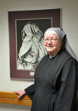 Mother Mary Vincent Mannion, superior of the Little Sisters of the Poor at the St.&nbsp;Augustine Home for the Aged in Indianapolis, poses for a recent photo beside a portrait of St. Jeanne Jugan, the order's foundress, at the home for the elderly poor. Residents enjoy the opportunity to participate in Mass each day at the home's chapel. (Photo by Mary Ann Garber)