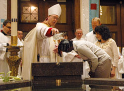 Bishop Christopher J. Coyne baptizes Tomiko Whitaker during the celebration of the Easter Vigil on April 23, 2011, at SS. Peter and Paul Cathedral in Indianapolis. Jerry Galooley, right, served as Whitaker&rsquo;s sponsor. (File photo by Sean Gallagher)