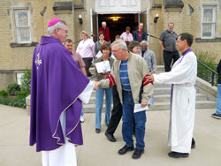 Bishop Christopher J. Coyne and Father Steven Schaftlein greet parishioners as they leave Mass at St. Francis Xavier Church in Henryville on March 25. The bishop pledged the archdiocese&rsquo;s long-term assistance to the parish and community as they rebuild from the destructive March 2 tornadoes. (Photo by Patricia Happel Cornwell)