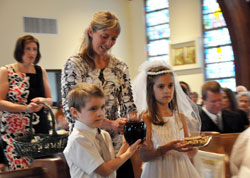 Trevor Langley, front left, and Lily Thomas, right, bring up the offertory gifts during the first&nbsp;Communion Mass on April 22 at St. Ann Church in Terre Haute. Catechist Lisa Ferguson, back left, and religious education coordinator Marti Goodwin help the children. (Photo by Mary Ann Garber)