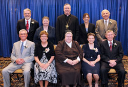 Two individuals, two married couples and two communities of religious sisters received Spirit of Service Awards during the April 26 dinner in Indianapolis. Award recipients, seated from left, are Pat Jerrell, Elaine Jerrell, St. Francis of Perpetual Adoration Sister M. Angela Mellady, Mary Pitzer and Fred Pitzer. Standing, from left, are award recipients William Spangler and Daughter of Charity Sister Catherine Kelly with Bishop Christopher J.&nbsp;Coyne, keynote speaker Allison Melangton and award recipient Tom Egold. (Photo by Rob Banayote)