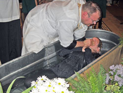 Father Ryan McCarthy, pastor of St. Michael Parish in Brookville and Holy Guardian Angels Parish in Cedar Grove, baptizes Ashley Tebbe on April 7 during St. Michael&rsquo;s Easter Vigil Mass. Good communication among a parish&rsquo;s pastor and parishioners interested in evangelization can help bring people to consider being welcomed into the full communion of the Church, says Peg McEvoy, archdiocesan associate director of evangelization and family catechesis. (Submitted photo)