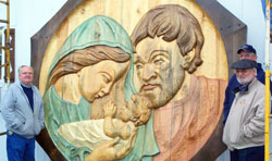 The Weberding brothers stand by the 10-foot high, 400-pound carving of the Holy Family that they created in honor of their late parents, William J. and Monica Weberding. The brothers&mdash;Tim, left, William G., right foreground, and Terry, right background&mdash;have continued to operate the Weberding Carving Shop in Batesville that their father started 70 years ago. (Submitted photo)