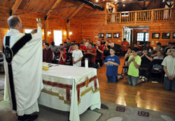 More than 40 junior high and high school-age boys kneel in prayer while Father Patrick Beidelman elevates a chalice during a June 13 Mass at the Future Farmers of America Leadership Center in Johnson County. The Mass was part of Bishop Brut&eacute; Days, a vocations camp and retreat experience sponsored by Bishop Simon Brut&eacute; College Seminary in Indianapolis, where Father Beidelman serves as vice rector. (Photo by Sean Gallagher)