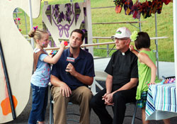Painting faces always adds a festive touch at parish festivals&mdash;a touch experienced by television reporter Keith Kaiser and Father H. Michael Hilderbrand, pastor, during the &ldquo;Knobs Fest&rdquo; at St. Mary-of-the-Knobs Parish in Floyd County in June of 2011. Kaiser and Father Hilderbrand benefited from the artistic talents of young parishioners Zoe Libs, left, and Chloe Sprigler. (Submitted photo)