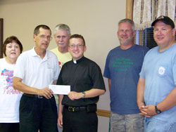Father Steven Schaftlein, second from left, wanted to share a $100,000 donation for tornado relief that he had received as the pastor of St.&nbsp;Francis Xavier Parish in Henryville with the people of Holton, another community devastated by the March 2 storms. So he made the check presentation during a surprise visit at a meeting of the Holton Long Term Recovery Group. He is pictured with, from left, Cynthia Melton, case manager of the group; Norm Knudson, the group&rsquo;s secretary/treasurer; Father Shaun Whittington, pastor of St. John the Baptist Parish in Osgood; Darin Kroger, the group&rsquo;s construction manager; and Philip Diewert, the group&rsquo;s volunteer manager. (Submitted photo)