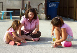 Cami Pritchett takes time from her duties as the director of Becky&rsquo;s Place, a Catholic Charities homeless shelter for women and children in Bedford, to draw chalk art with two girls who are residents of the facility that opened this year. (Submitted photos by Corrina Cazares)