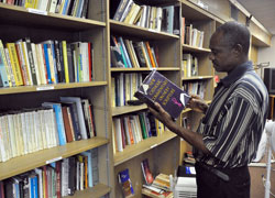 Alex Ogbuh, a maintenance worker at St. Rita Parish in Indianapolis, looks at a book on Sept. 17 in the parish&rsquo;s library. In 2011, St. Rita Pasrish received a Growth and Expansion grant from the archdiocese to expand the holdings of the library. Recent changes to the application process for archdiocesan grants will make more funds available more often to parishes across central and southern Indiana. (Photo by Sean Gallagher)