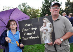 Our Lady of the Most Holy Rosary parishioners Tamara Richards, left, and her father, Kevin Richards, of Indianapolis hold a pro-life sign as they pray in front of the Planned Parenthood abortion facility in Indianapolis on Sept. 26 as part of the fall rally for the &ldquo;40 Days for Life&rdquo; campaign. (Photo by Mary Ann Garber)