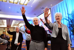 Franciscan Sisters Rita Vukovic, from left, Jan Kroeger and Jacquelyn McCracken raise their hands as they sing &ldquo;The Blessing of St. Clare&rdquo; with other sisters at the conclusion of Marian University&rsquo;s 75th anniversary awards dinner and celebration on Oct. 19 in downtown Indianapolis. (Photo by Mary Ann Garber)