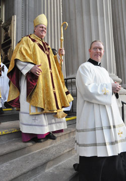 Archbishop Joseph W. Tobin smiles as he walks out of SS. Peter and Paul Cathedral in Indianapolis after the Dec. 3 Mass in which he was installed as the sixth archbishop of Indianapolis. Walking in front of Archbishop Tobin is Father Patrick Beidelman, archdiocesan director of liturgy. (Photo by Sean Gallagher)