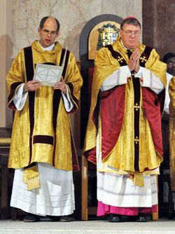 Deacon Russell Woodard, left, reads the general intercessions during the Dec. 3 installation Mass of Archbishop Joseph W. Tobin, right, as the sixth&nbsp;archbishop of Indianapolis in SS. Peter and Paul Cathedral in Indianapolis. Deacon Woodard is parish life coordinator of St. Anne Parish in New Castle and St. Rose of Lima Parish in Knightstown. He also is involved in the ministry of charity at the New Castle Correctional Facility. (Photo by Sean Gallagher)