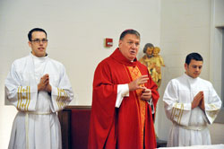 Archbishop Joseph W. Tobin, center, speaks during a Mass on Oct. 18 at Bishop Simon Brut&eacute; College Seminary in Indianapolis. Later that day, he was introduced as the sixth archbishop of Indianapolis. Assisting Archbishop Tobin are, left, seminarians Timothy DeCrane, a member of Most Holy Name of Jesus Parish in Beech Grove, and Anthony Stange, a member of St. Lawrence Parish in Lawrenceburg. (File photo by Sean Gallagher)